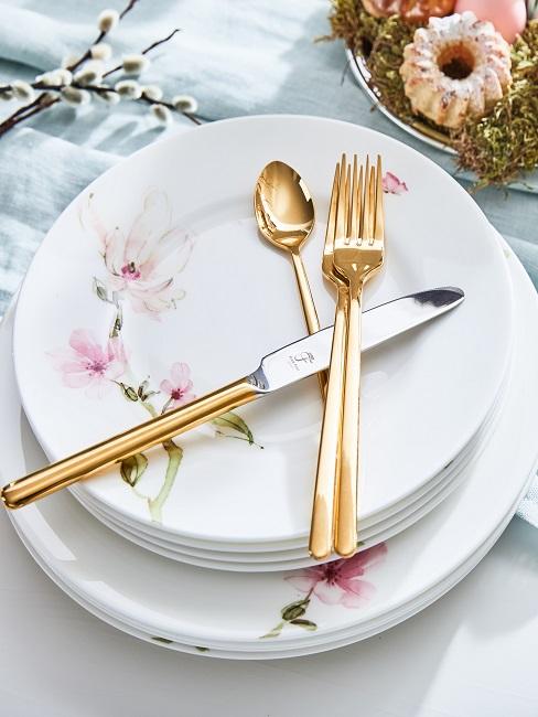 Goldenes Besteck auf Tellern mit Blumenverzierung