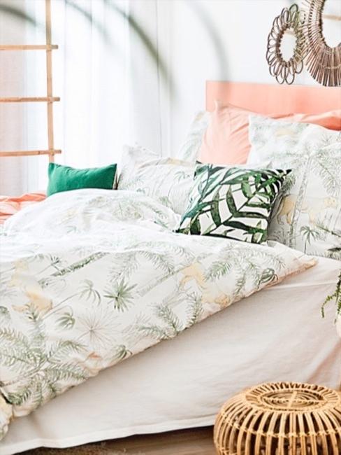 Pastelloranges Bett mit Bettwäsche in Dschungel Optik und Holz Nachttisch sowie Rattanhocker