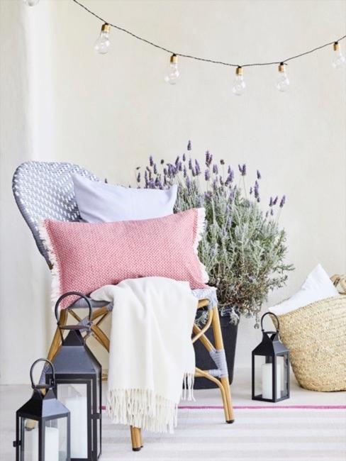 Esquina acogedora con silla gris y cojines, luces y maceta con planta de lavanda