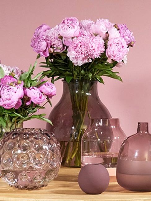 Tisch mit verschiedenen lila Vasen und Blumen