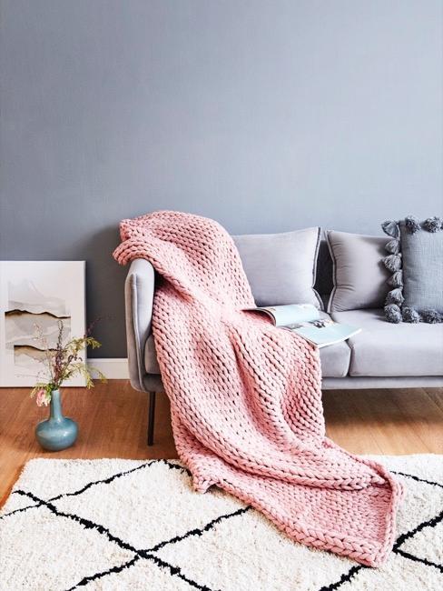 Colores para paredes Salón con pared de color azul plomo y sofá gris con manta rosa de punto