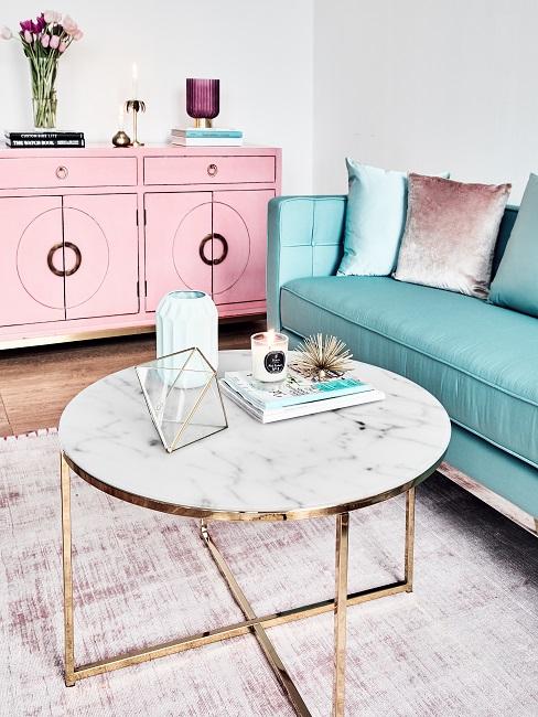 Moderner Couchtisch mit weiÃer Marmorplatte vor einem grünen Sofa und einem rosafarbenen Sideboard