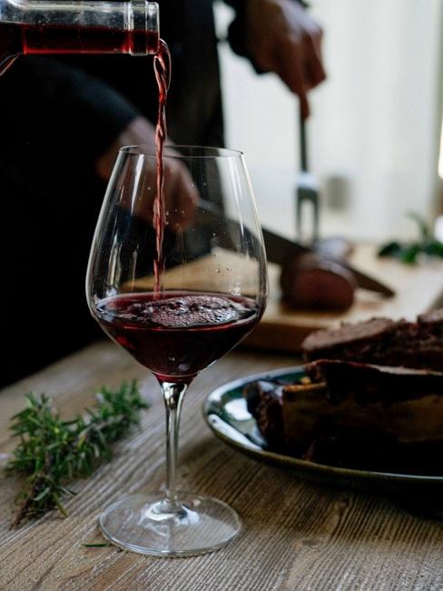 Rotweinflecken entfernen Nahaufnahme Rotweinglas mit Rotwein auf Esstisch