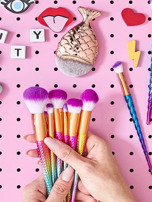 Organización de productos pinceles para maquillaje en un fondo rosa
