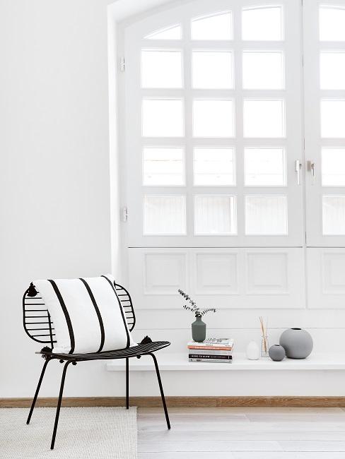 Slow Living Stuhl in Schwarz mit einem schwarz-weißen Kiseen neben einer Terassentüre