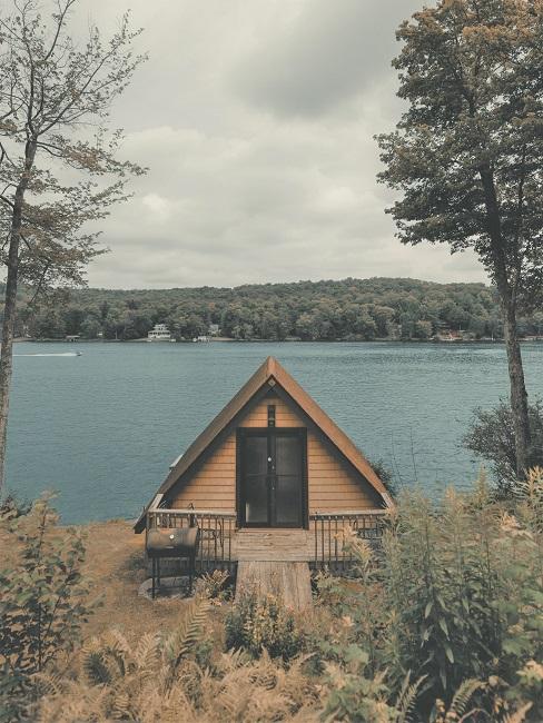 Tiny House Ein Tiny House steht auf einem Grundstück am See umgeben von Gräsern und Bäumen.