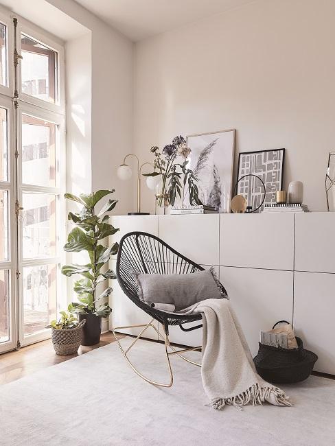 Schwarzer Acapulco Chair im Zimmer dekoriert mit Kissen und Decke neben Kommode und Pflanze