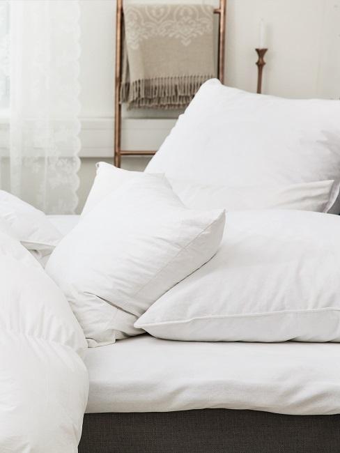 kopfkissen waschen Ein Bett mit strahlend frischer Bettdecke in Weiß und mehreren Kissen
