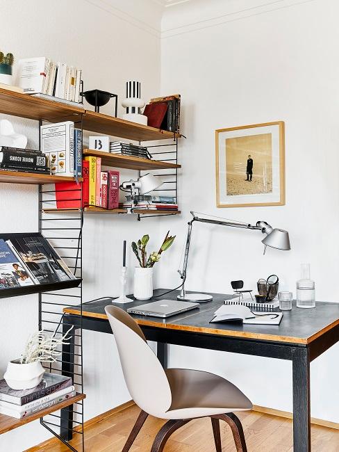 Arbeitsplatz mit moderner Einrichtung: Einem Schreibtisch in Schwarz mit puristischer Deko und einem String Regal mit Büchern