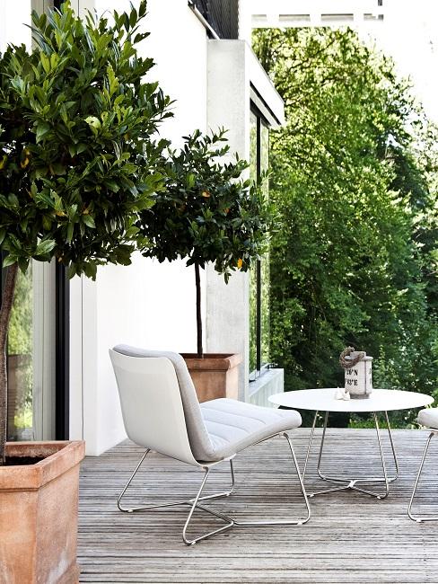 Terrasse von einem modernen Haus in Weiß mit zwei Terrassenstühlen und einem runden Tisch