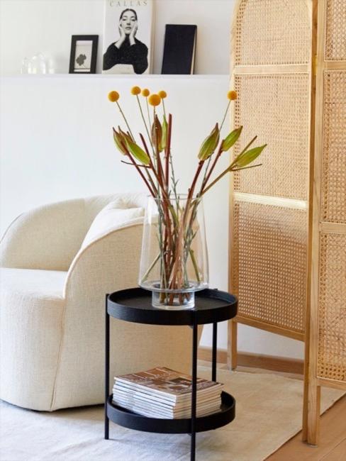 Sillón de bouclé blanco, diván de mimbre y mesa auxiliar con jarrón de flores