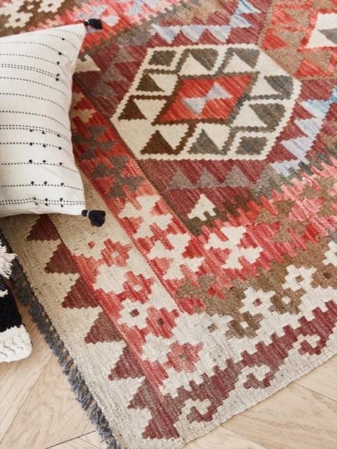 Alfombra de motivos geométricos y cojÃn con flecos