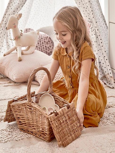 Ostergeschenke Kinder Kleines Mädchen öffnet freudig einen Picknickkorb.