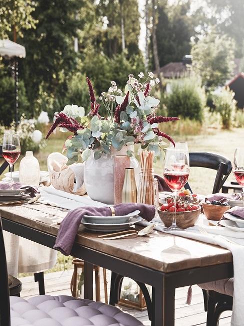 Grillparty Gedeckter Tisch mit Blumen und Wein im Garten