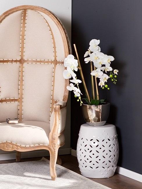 Decoración con orquÃdeas blancas sobre un taburete al lado de un sillón