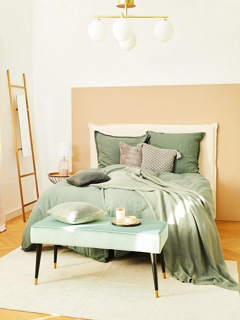 Schlafzimmer mit grüner Bettwäsche und einer grünen Bettbank vor dem Bett