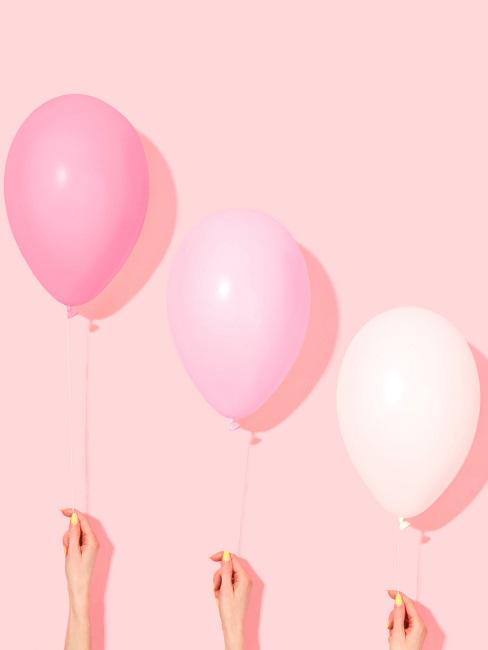 JGA Deko Rosafarbene Hand, davor drei rosa Luftballons, gehalten von Frauenhänden