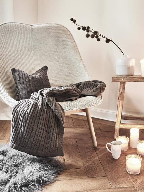 reducir-el-estres Sillón crema con manta y cojín gris oscuro y velas