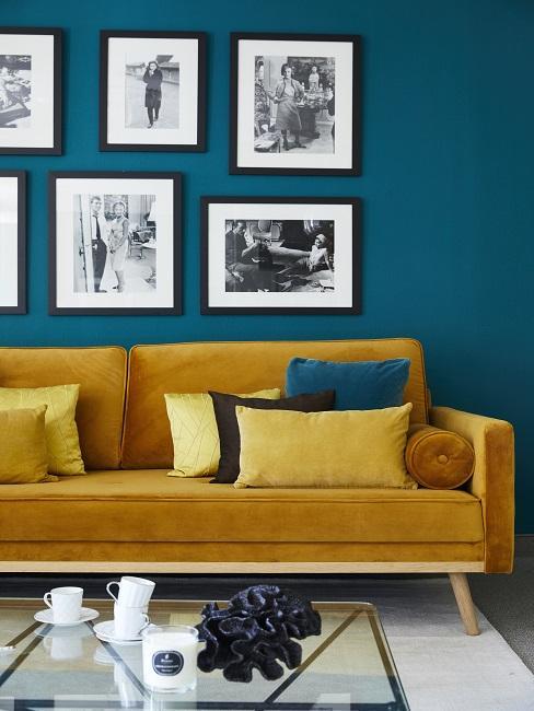 como-colgar-fotos Salón con pared azul con cuadros y sofá amarillo mostaza