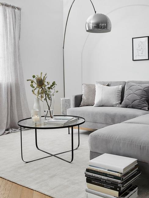 Coin salon avec canapé gris, tapis blanc et lampe en métal
