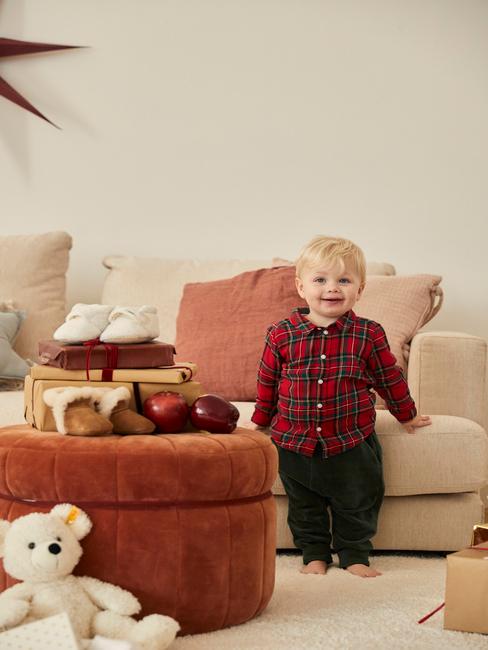 Coin-jeux Petit garçon dans un salon avec des jouets sur un grand pouf rouge