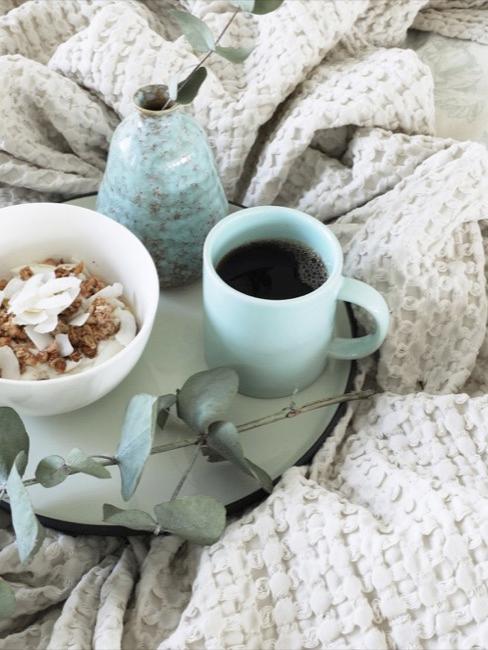 Plateau avec café et müsli placé sur la couverture d'un lit