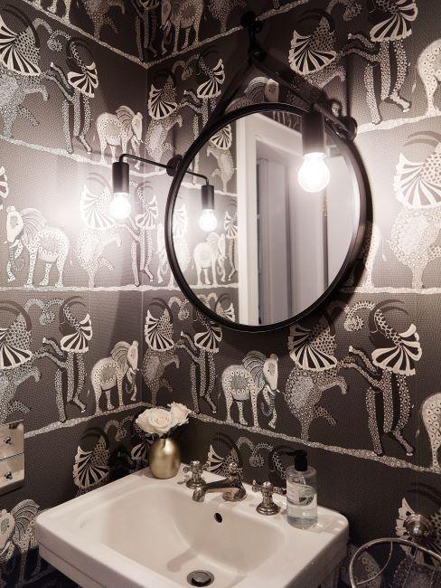 bagno nero bagno con parete nera con motivi bianchi e specchio rotondo