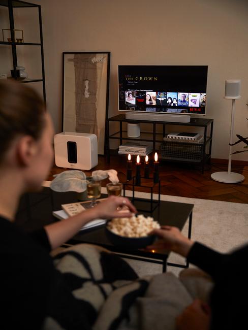 Wieczór filmowy Fragment salonu z białym dywanem, czarnym stolikiem kawowym oraz telewizorem