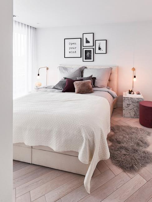 BiaÅa sypialnia w stylu glam w poduszkami i obrazkami na Åcianie