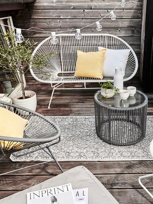 Drewniany balkon z meblami ogrodowymi oraz roÅlinÄ
w biaÅej doniczce