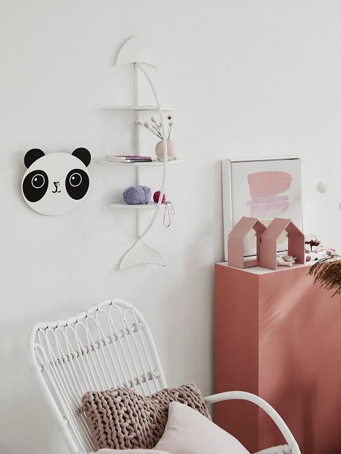 Wandregal neben Pandauhr über einem Schaukelstuhl im Kinderzimmer