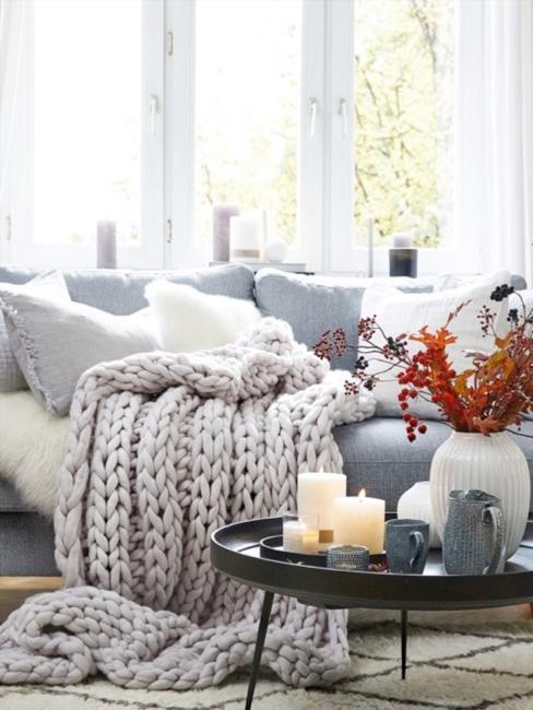 Chunky knit Grobstrick Decke Wohnzimmer Dicke gemütliche Chunky Knit Grobstrick Decke auf dem Sofa, daneben ein schön dekorierter Couchtisch