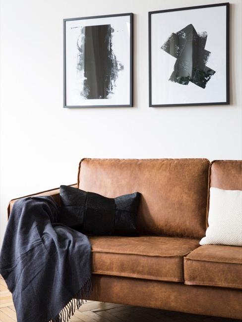 Skórzana sofa nad którą wiszą czarno-białe grafiki.