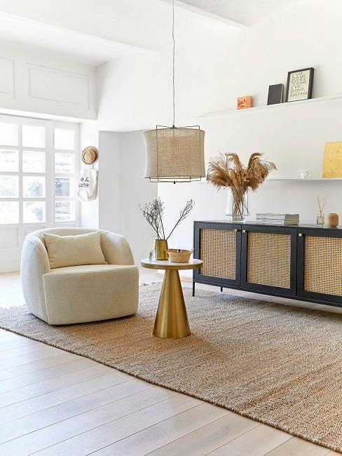 Intreccio Viennese Credenza con lavorazione di intrecci viennesi in un soggiorno dai toni naturali, dietro un tappeto in sisal con tavolino dorato e una poltrona in ecrù.