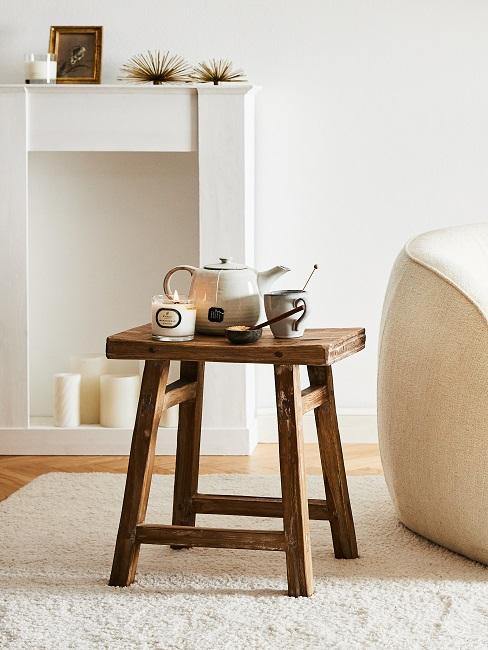 Nachhaltige Möbel Hocker aus recyceltem Holz steht im Wohnzimmer mit einer Duftkerze und einer Kanne Tee mit passender Teetasse.