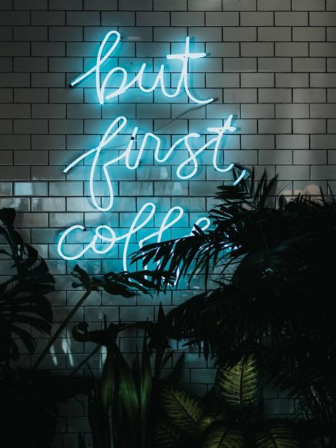 Neon-Leuchtschrift Neon-Leuchtschrift an einer weißen Fließenwand mit den Worten "But first Coffee".