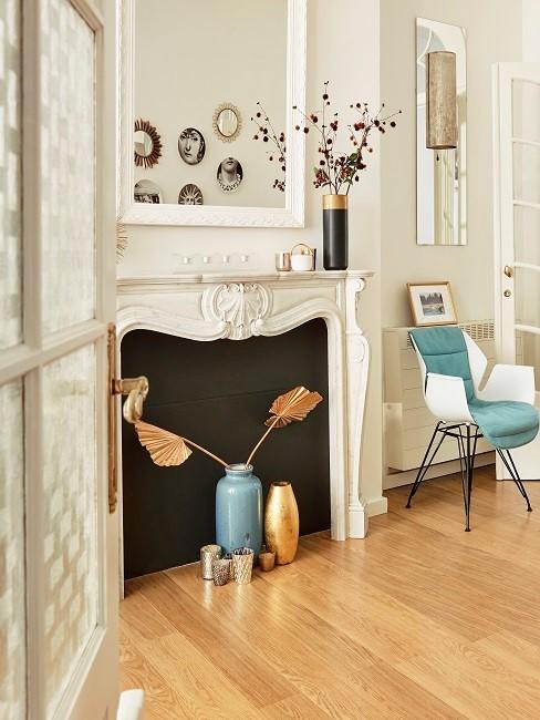 Weißes Kaminzimmer mit blauem Stuhl, blauer Vase und goldener Deko