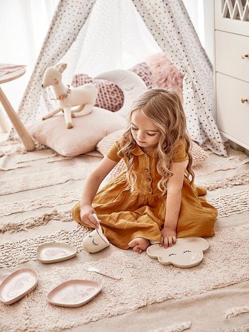 Kind spielt im rosa Kinderzimmer mit Spielzeug
