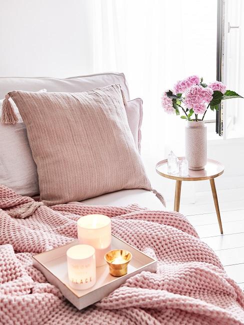 Tablett mit Kerzen auf rosa Plaid auf einer Couch