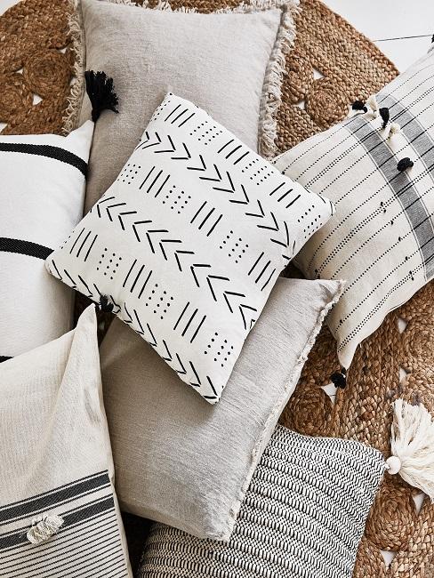 Boho Kissen Viele helle Boho Kissen, teilweise mit Muster, liegen übereinander auf einem Jute Teppich