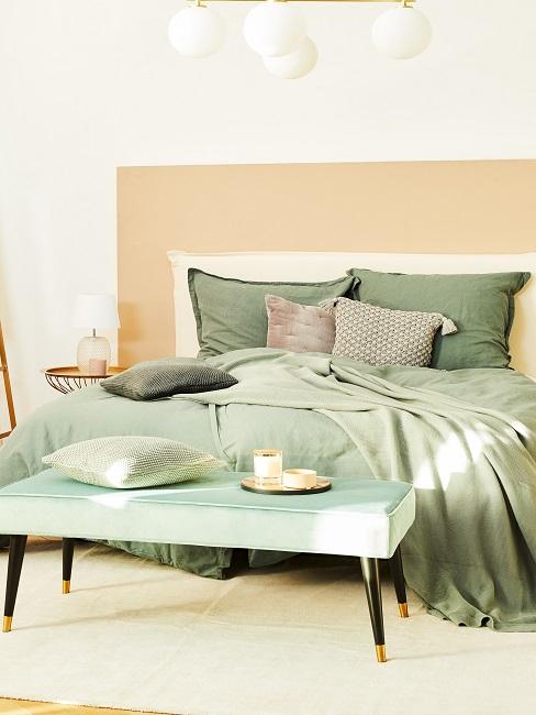 Doppelbett mit grüner Bettwäsche und Sitzbank davor