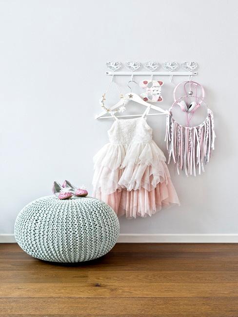 Garderobe mit Mädchenteilen neben einem Pouf