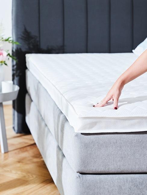 Hand berührt Matratze auf Bett