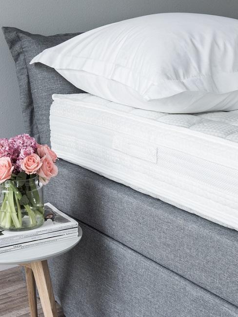 Matratze und Kissen auf Bett neben Beistelltisch