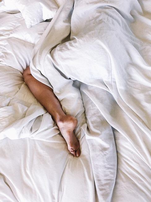 Bein umhüllt mit Decke in Bett