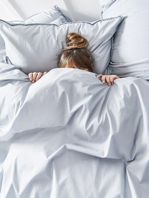 Person zugedeckt im Bett