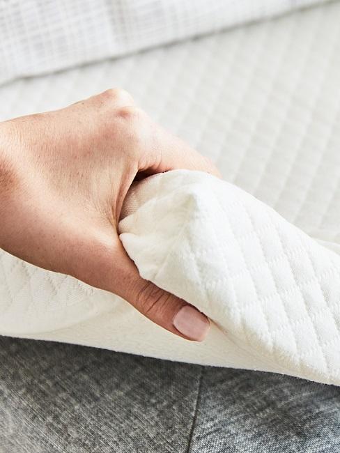 Hand hebt Matratzen-Topper hoch