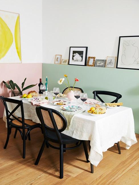 Esszimmer mit pastellfarbenen Wänden, schwarzen Stühlen und Bilderdekoration