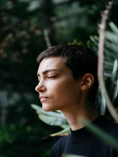 Chica con ojos cerrados en medio de un bosque tropical