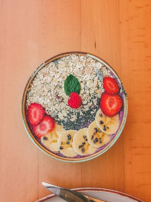 desayuno-saludable-banner Bol con copos de avena, fresas y plátanos en rodajas, semillas chia y una frambuesa